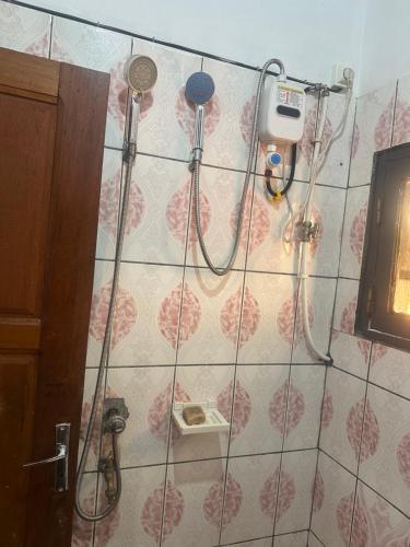 prysznic w łazience z różowymi i białymi płytkami w obiekcie Colbel appartement w mieście Jaunde