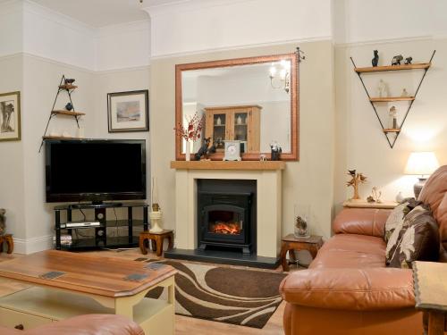 a living room with a fireplace and a television at Chestney House in Hunstanton