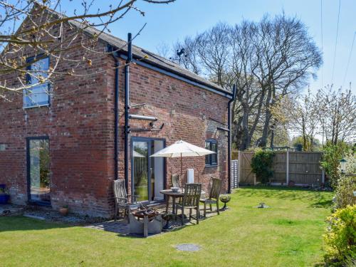 a brick house with a table and an umbrella at The Stables in Knutsford