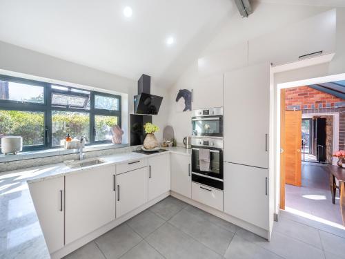 a kitchen with white cabinets and a large window at Lower Peastocking in Meriden
