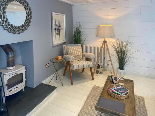 a living room with a chair and a fireplace at Gylly Cottage in Mousehole