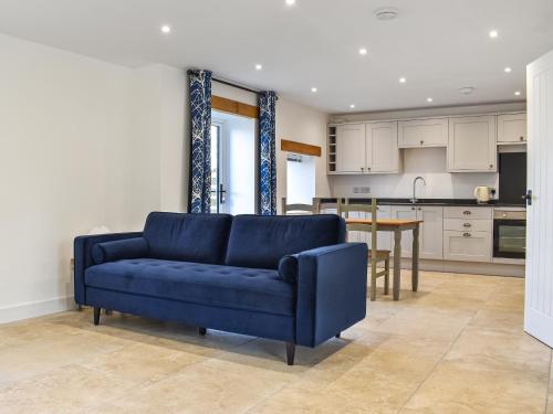 a living room with a blue couch and a kitchen at Lavender Cottage -Uk49209 in Jacobstowe