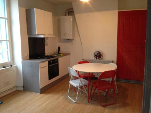 a kitchen with a table and chairs and a red door at Grand 2 pièces lumineux plein centre ville in Romans-sur-Isère