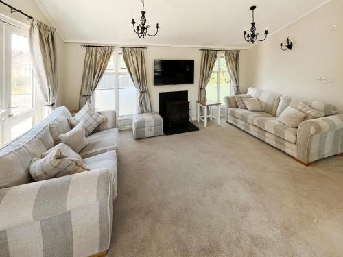 ein Wohnzimmer mit zwei Sofas und einem Kamin in der Unterkunft The Lodge in Chapel Saint Leonards