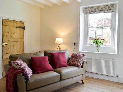 a living room with a couch and a window at The Cottage At 1710 in Castle Carrock