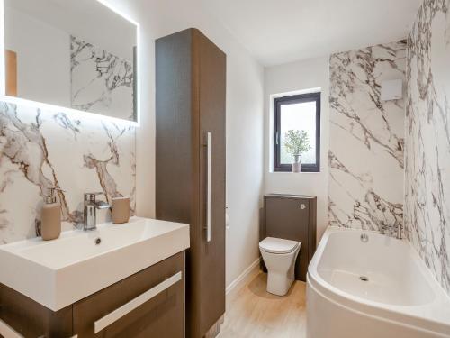 a bathroom with a sink and a toilet and a tub at Bumble Bee Farm in North Tuddenham
