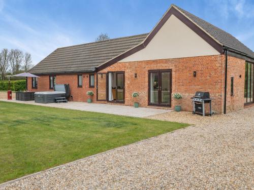 a brick house with a grill in a yard at Bumble Bee Farm in North Tuddenham