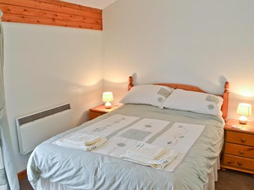 a bedroom with a bed with two night stands and two lamps at Brambles in St. Agnes