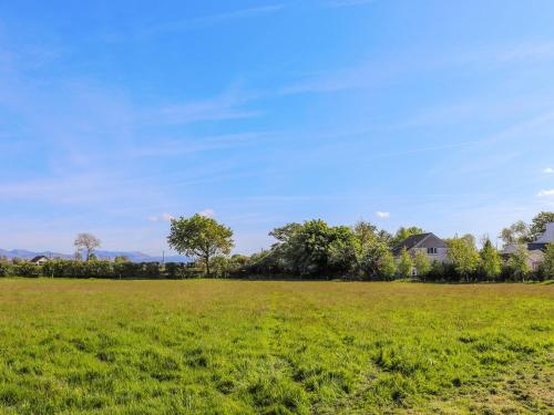 a field of green grass with houses in the background at Awel Deg - Uk49672 in Brynsiencyn