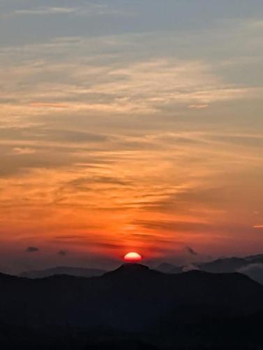 a sunset with the sun setting on top of a mountain at Eagle View villa in Ella