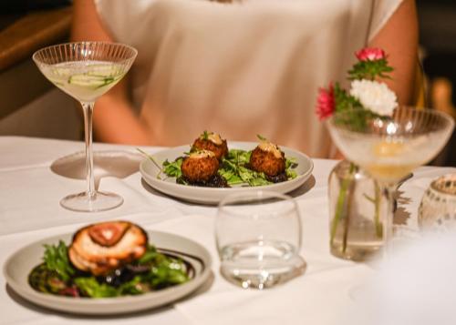 a table with plates of food and glasses of wine at The Bakery B&B in Westerham