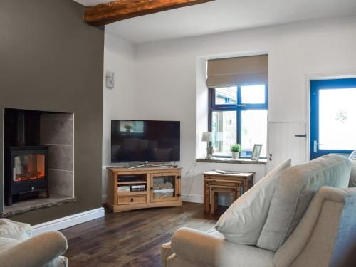 a living room with a couch and a fireplace at Doorstones Cottage in Moorside