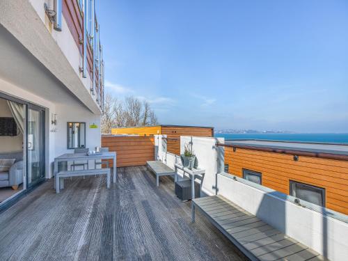 einen Balkon mit Bänken und einem Tisch auf einem Gebäude in der Unterkunft 5 Curlew, The Cove in Brixham