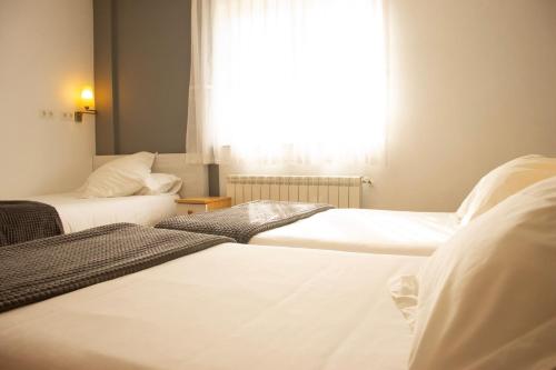 three beds in a room with a window at Hotel La Casa Del Abuelo in Tapia de Casariego