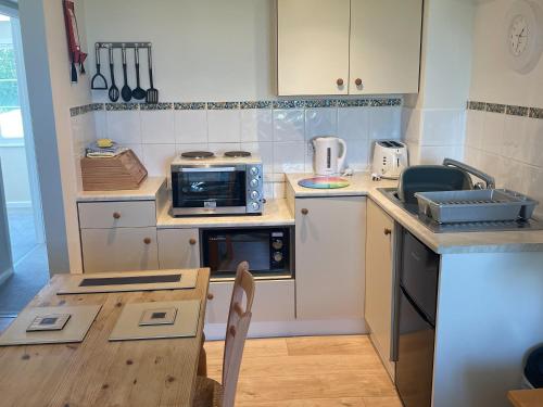 a small kitchen with a table and a microwave at Goldfinch Apartment - Uk49296 in Woolfardisworthy
