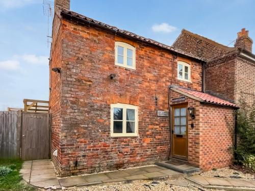 an old brick house with a brown door at Butterfly Cottage in Maltby le Marsh