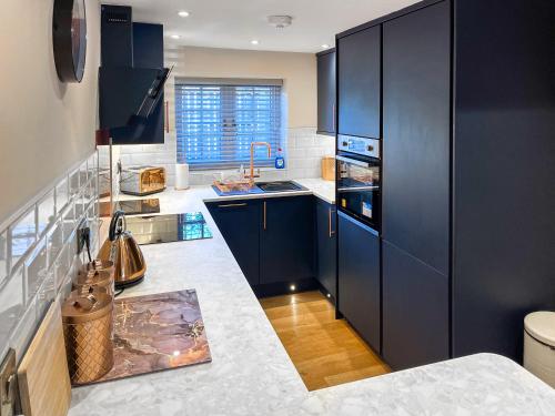 a kitchen with dark blue cabinets and a sink at Lily Pad - Uk49104 in Helmsley