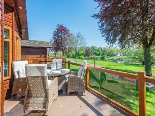 a patio with a table and chairs on a deck at Willowbank Lodge in Stratford-upon-Avon