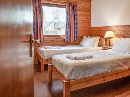 two beds in a room with a window at Macallan Lodge - Uk49119 in Feshiebridge