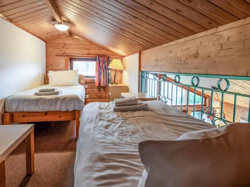 two beds in a room with a balcony at Macallan Lodge - Uk49119 in Feshiebridge