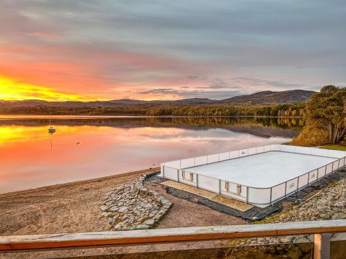a building on the shore of a lake at sunset at Macallan Lodge - Uk49119 in Feshiebridge