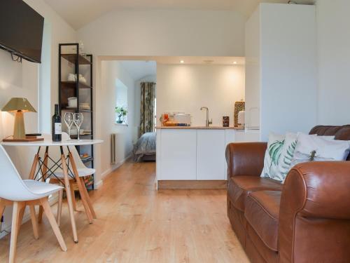 a living room with a brown couch and a kitchen at Garden Cottage in Thornton Dale