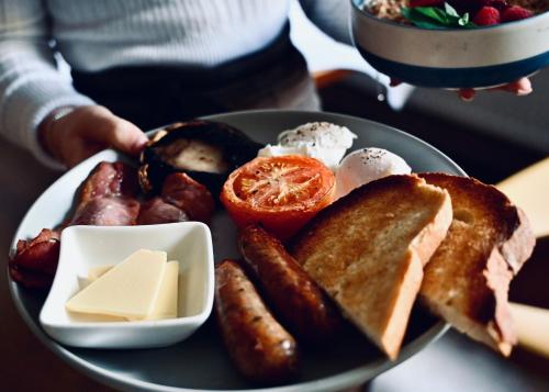 a plate of breakfast food with sausage and eggs at The Bakery B&B in Westerham