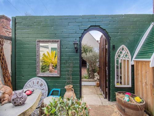 a green building with a mirror and a table at Hideaway in Beccles
