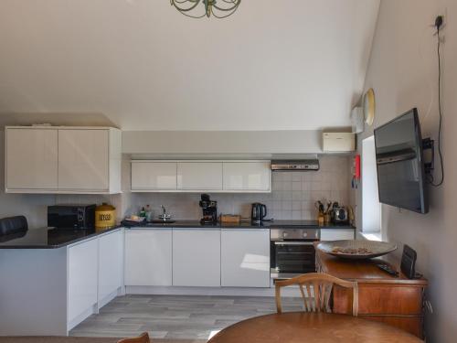 a small kitchen with white cabinets and a table at Holly No2 - Uk49254 in Althorne
