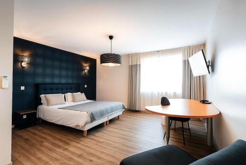 a bedroom with a bed and a table at Hôtel L'ange de la vallée in Oyonnax