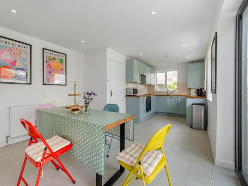 a kitchen with a table and colorful chairs at Beach House in Seaford