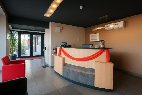 a lobby with a reception counter with a red cloth around it at Hôtel L'ange de la vallée in Oyonnax