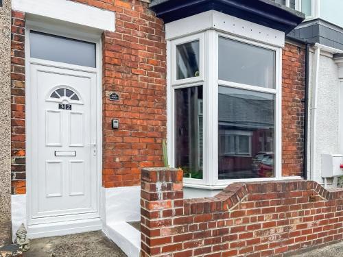 a brick house with a white door and a window at The Salthouse in Sunderland