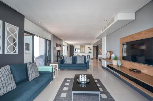 a living room with blue couches and a tv at Executive Apartment with Ocean Views in Blouberg in Big Bay