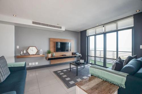 a living room with a blue couch and a tv at Executive Apartment with Ocean Views in Blouberg in Big Bay
