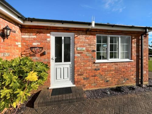 a brick house with a white door and windows at Bramble - Uk49172 in Burgh le Marsh