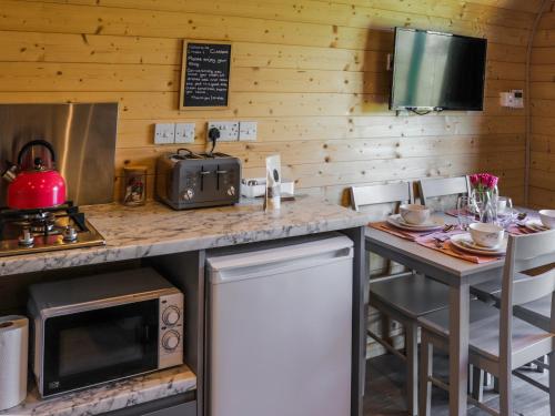 a kitchen with a counter and a table with chairs at Cuddfan - Uk49673 in Brynsiencyn