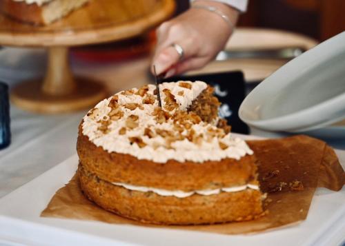 a person cutting into a cake with a knife at The Bakery B&B in Westerham