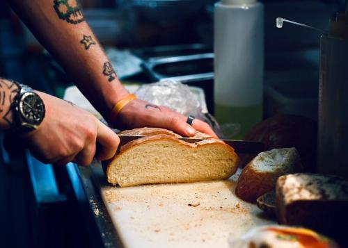 a person cutting a loaf of bread with a knife at The Bakery B&B in Westerham