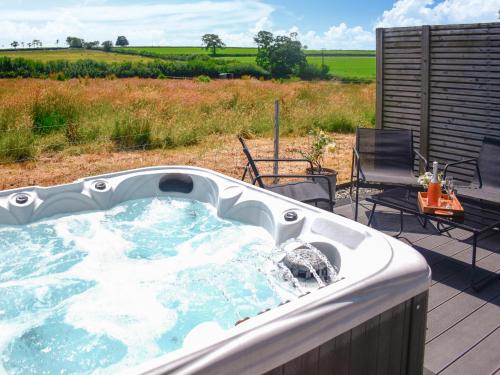 a hot tub on a deck with a table and chairs at The Old Hayloft - Uk49680 in Witheridge