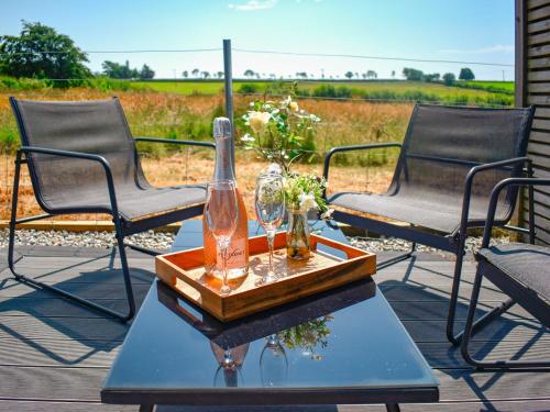 a table with a bottle and glasses on a patio at The Old Hayloft - Uk49680 in Witheridge