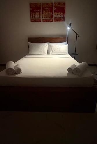 a bed with two pillows and a light on top at Eolie Weligama in Weligama