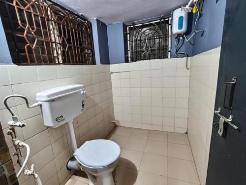 a bathroom with a toilet and a window at Kanasu guest house in Gokarna