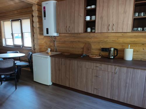 a kitchen with wooden cabinets and a white refrigerator at Відпочинкова база " На Нивці" in Stilskoye