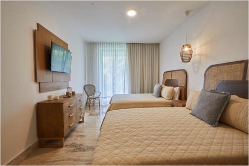 una camera d'albergo con due letti e una televisione di Apartamento Moderno en Playa Dorada Piscina & Playa a Puerto Plata