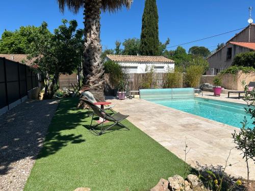 une cour avec une piscine et une chaise à côté d'un palmier dans l'établissement Cottage a Vidauban, à Vidauban