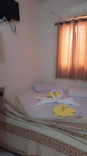 a bed with towels on it with a window at Pousadaa São João 144 in Aparecida