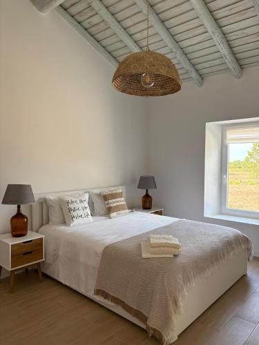 a white bedroom with a large bed and a chandelier at Casa da Moura in Santiago do Cacém