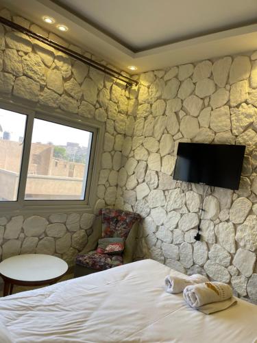 a bedroom with a rock wall with a bed and a tv at Cheristo pyramids view inn in Cairo