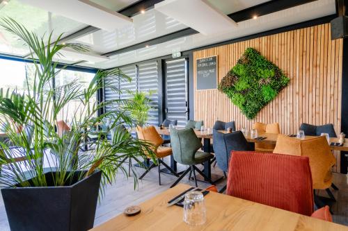 ein Restaurant mit Tischen, Stühlen und Pflanzen in der Unterkunft Domaine du Vieux Porche in Mignaloux-Beauvoir